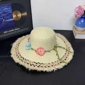 Detailansicht des handgefertigten Strohhutes mit Blumen- und Rankenverzierung im Sommer.