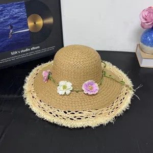 Detailansicht des handgemachten Bast-Sonnenhuts mit Blumendekor und ausgefranster breiter Krempe.