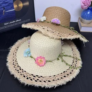 Detailansicht handgefertigter Strohhüte mit floralem Dekor und Fransenrand für den Sommer.