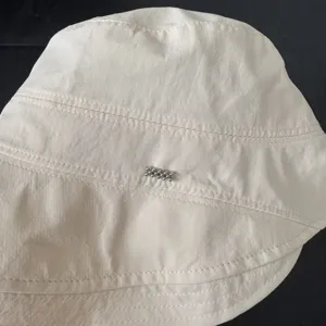 Vista detallada de un sombrero de pescador beige claro estilo japonés con cuentas de metal.