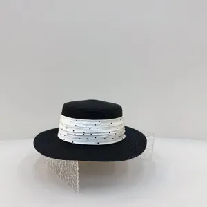 Detail view of a classic black straw boater hat featuring a stylish white polka dot ribbon band.