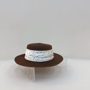Close-up detail of a brown flat top straw hat with a white polka dot scarf, elegant beachwear.