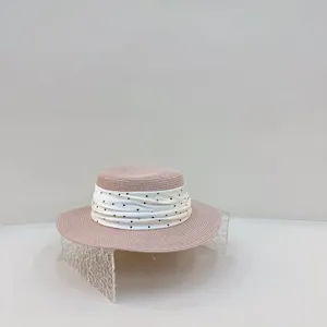 Detailed view of the pink straw sun hat featuring a cute white polka dot ribbon trim.