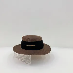 Detailed view of the brown straw boater hat with black ribbon and gold metal accent.