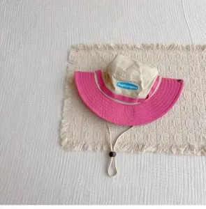 Outdoor sun protection bucket hat detail, contrast pink and beige brim, adjustable chin strap.