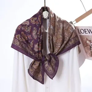 Close-up detail of luxury paisley print square scarf with double-sided color blocking.