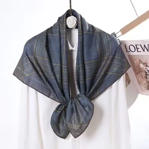 Detailed view of the blue-green plaid velvet square scarf draped on a white shirt prop.