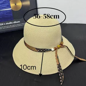 Straw sun hat detail showing wide brim and decorative ribbon with wooden beads and pearl.