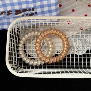 Vista dettagliata di elastici per capelli a spirale perlati in bianco e champagne, resistenti.