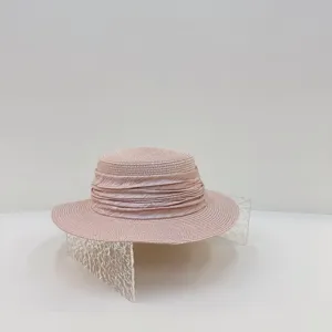 Vue détaillée du chapeau de paille rose à calotte plate, texture fine et ruban plissé.