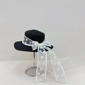 Chapeau de paille noir pour femme avec élégant nœud en dentelle blanche et détails de perles.