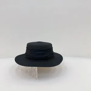 Gros plan d'un chapeau de paille noir élégant à calotte plate et ruban plissé chic.
