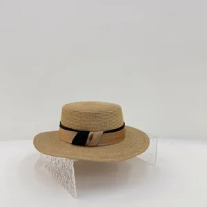 Detailansicht eines flachen Damen-Strohhutes mit elegantem kontrastierenden Schleifenband.