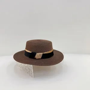 Detaillierte Ansicht des braunen Strohhutes mit eleganter schwarzer und khakifarbener Schleife.
