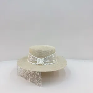 Close-up of the elegant straw hat featuring delicate white lace trim and bow detail for summer.