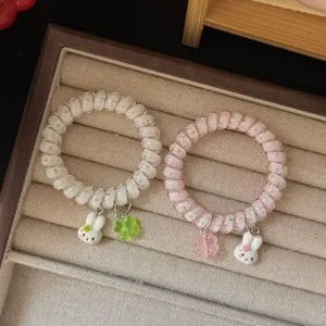 Primo piano di elastici per capelli a spirale con graziosi ciondoli a forma di coniglietto e trifoglio.