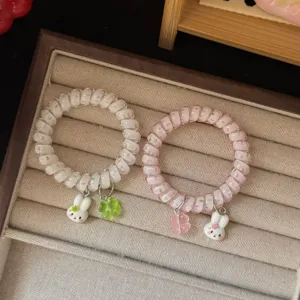 Primo piano di simpatici elastici per capelli a spirale con ciondoli coniglio e trifoglio.