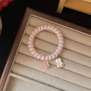 Dettaglio elastico capelli filo telefono rosa con graziosi ciondoli coniglio e trifoglio.