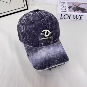 Detailansicht der stylischen Destroyed-Baseballkappe mit Batikmuster und Stickerei.
