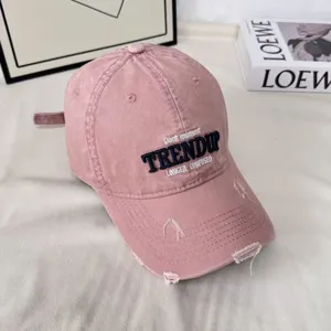 Primer plano de gorra de béisbol rosa vintage, algodón lavado con detalles de bordado.