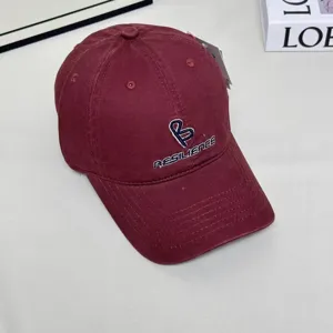 Burgundy baseball cap front embroidery detail showing stylized letter B and resilience text logo.