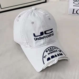 Detailed view of grey distressed baseball cap with heavy embroidery and street fashion style.