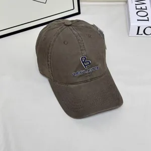 Detail shot of dark grey baseball cap featuring front letter embroidery and curved brim design.
