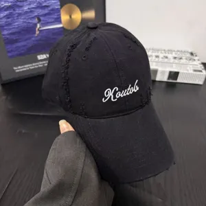 Detailed close-up of a black distressed cotton baseball cap with white embroidered script.