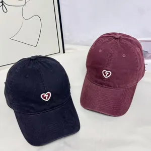 Embroidered heart baseball cap detail showing black and maroon caps with cute design.