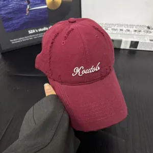 Detail shot of burgundy distressed cotton baseball cap, soft top design, curved brim.