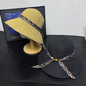 Summer straw sun hat with wide brim, fashionable geometric ribbon and wooden bead decor.