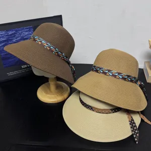 Detail view of woven straw sun hats with ribbon decor, placed on a dark table surface.