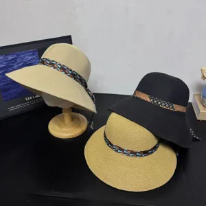 Close-up detail of stylish woven straw sun hats featuring patterned ribbons on dark table.