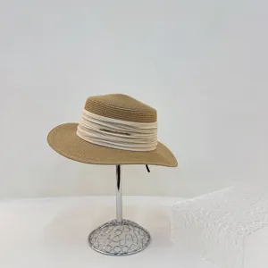 Detail view of a vintage beige straw hat with pleated ribbon and metallic bar decoration.
