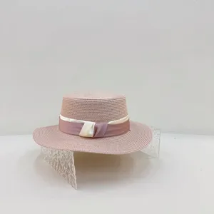 Detailansicht des eleganten rosa Strohhutes mit zweifarbigem Band und flacher Krone.