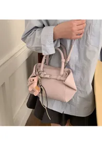 Minimalist women crossbody handbag detail view, elegant pink design with cute charm accessory.