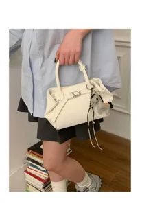 Close-up of the stylish white handbag featuring a cute leather horse charm and handle.