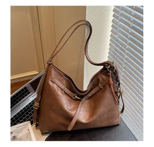 Brown PU leather underarm shoulder bag with metal hardware and strap detail in daily scene.