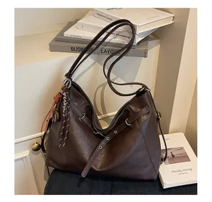 Detail view of dark brown leather shoulder bag, showcasing soft texture and hardware.