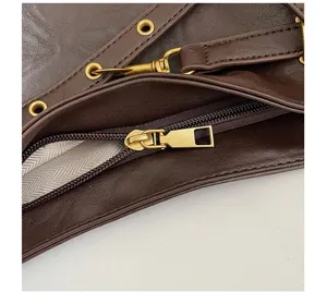 Close-up detail of brown faux leather shoulder bag with vintage gold metal hardware and zipper.