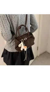 Chic brown leather shoulder handbag for women, featuring a cute horse charm and minimalist style.