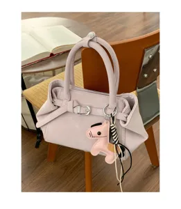 Detailed view of stylish pink women handbag featuring elegant buckle and cute horse charm.