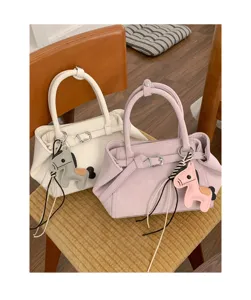 Detailed view of stylish women handbags in white and purple with cute leather horse charms.