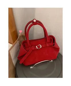 Red suede handbag detail showcasing metal buckle closure and structured dual top handles.