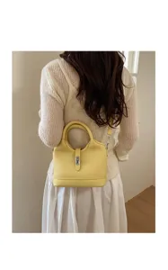 Detail shot of a chic yellow leather shoulder bag worn on back, elegant commuting style.