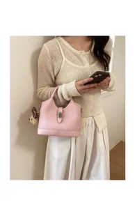 Detail view of the pink leather bucket bag with lock closure and cute bear pendant charm.