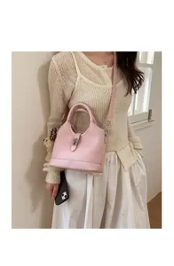 Close-up detail of a stylish pink leather bucket handbag with metal lock and cute charm.