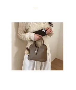 Detailed view of the brown leather bucket bag with metal lock and cute bear pendant.