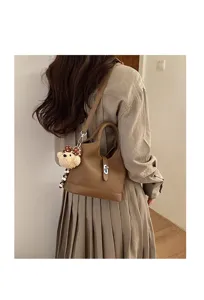 Stylish Korean style PU leather bucket bag with cute bear charm for daily commute.