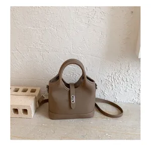 Taupe leather bucket bag with top handle and shoulder strap for women daily commuting.